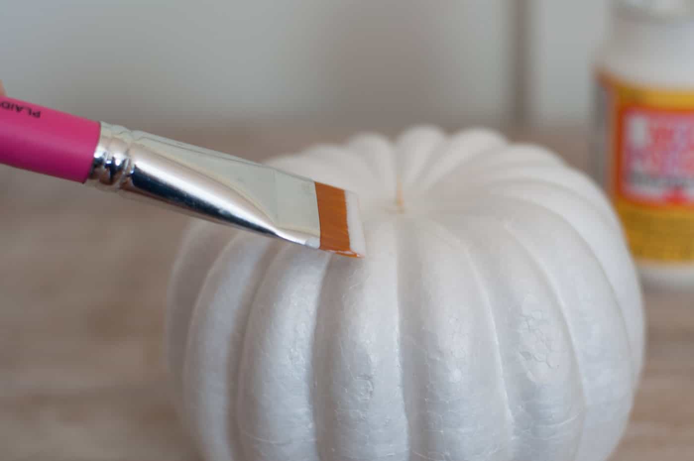 Applying Mod Podge to the foam pumpkin