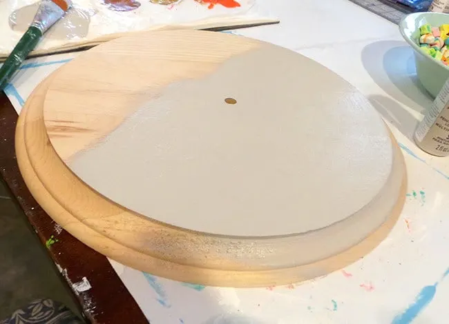 Unfinished wood clock base being painted with linen paint