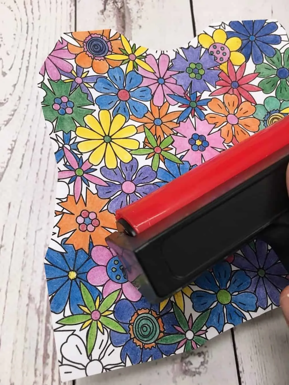 Applying a brayer to the top of the coloring page on the wood letter