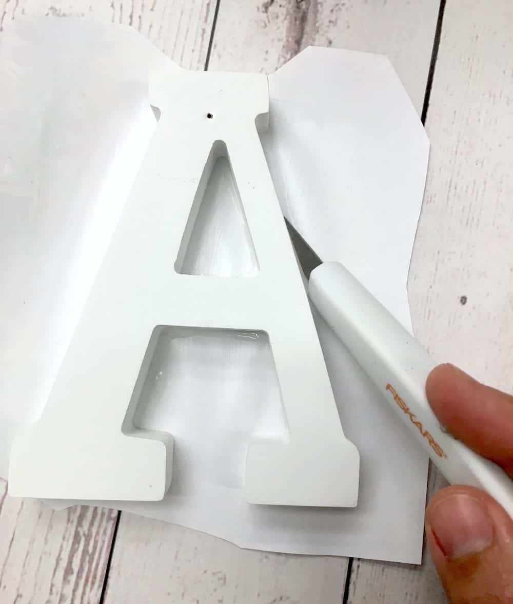 Trimming the page from around the wood letter with a craft knife