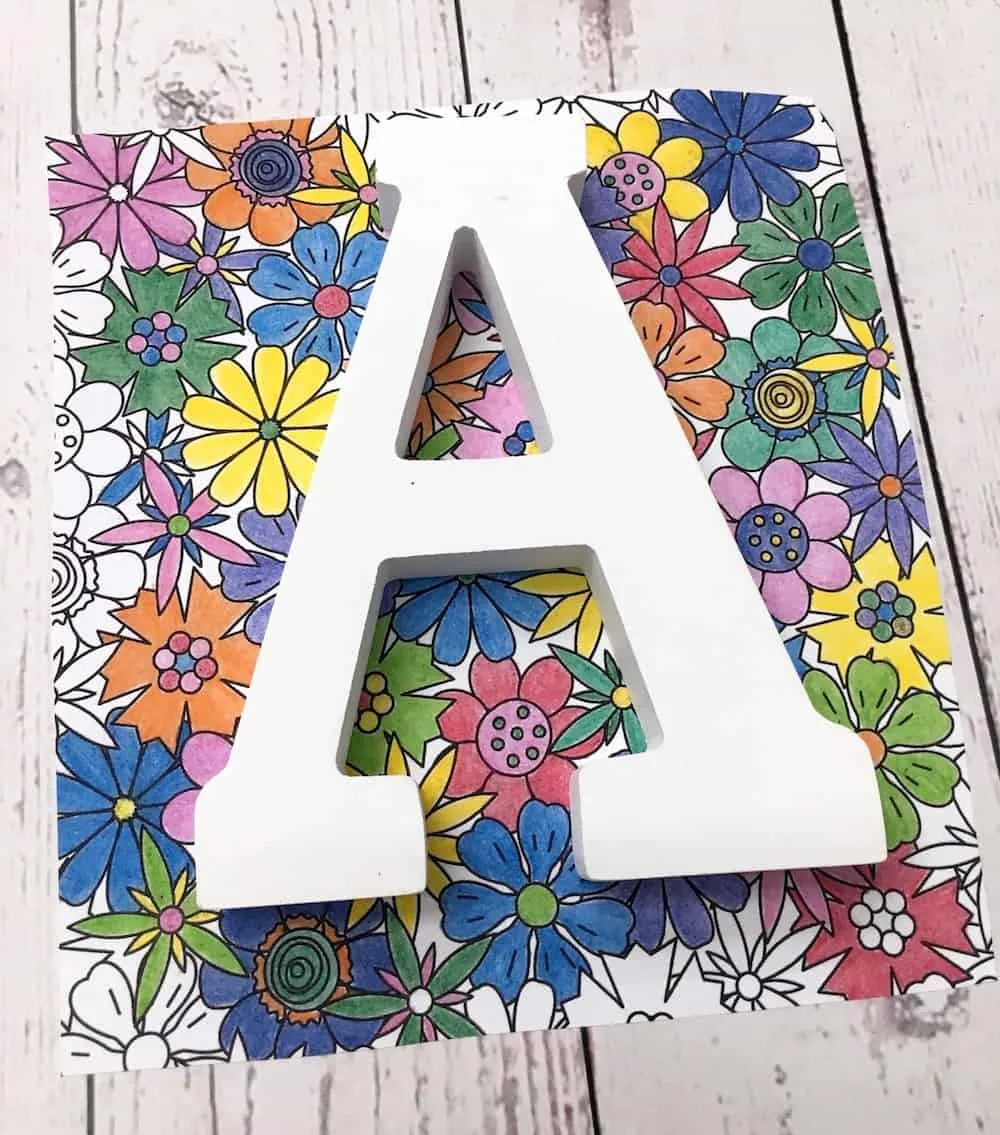 White letter placed on top of a cut out coloring page