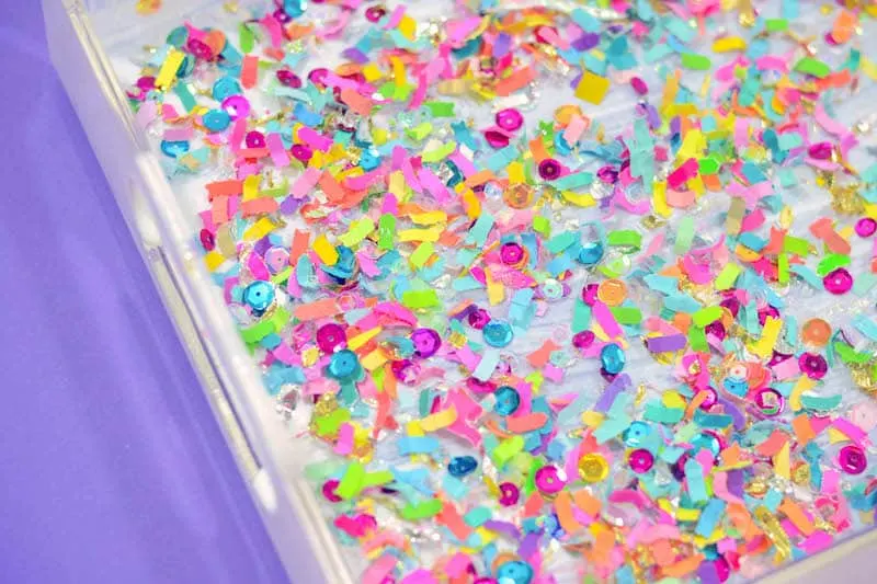 Confetti sprinkled on top of wet Mod Podge inside a clear tray