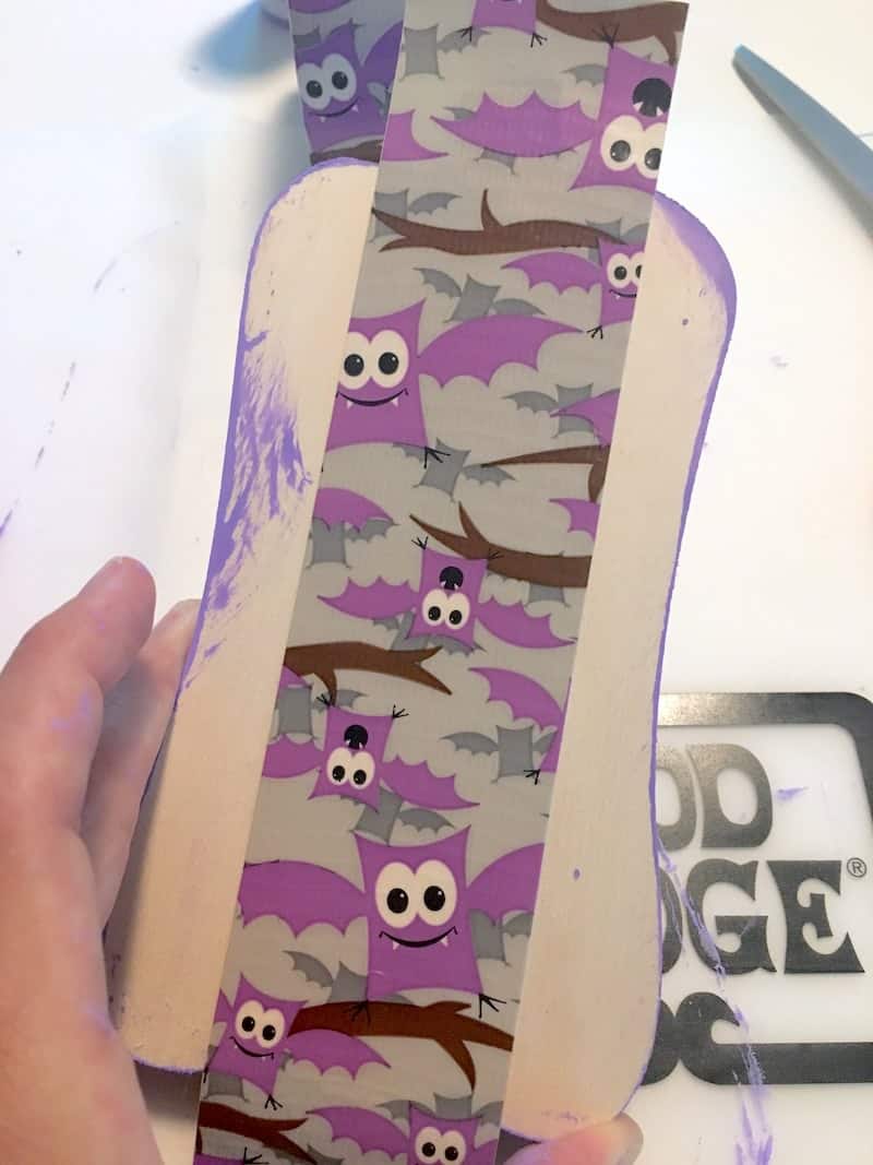 Applying bat Duck Tape to a wood letter