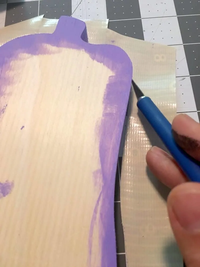 Trimming Duck Tape from around the O wood shape with a craft knife