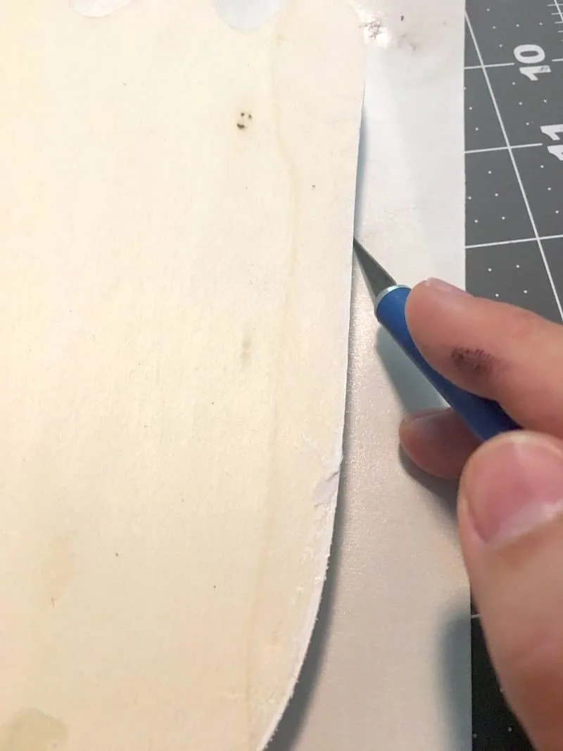 Trimming Duck Tape off the edge of a wood letter using a craft knife