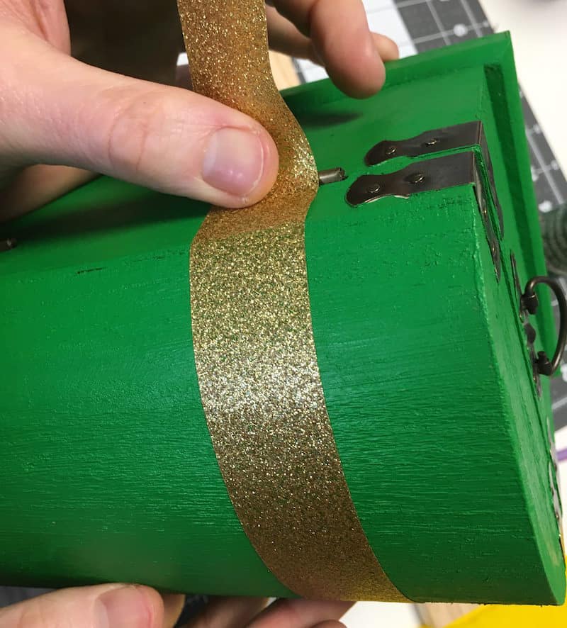 Taping a wood treasure chest with gold glitter tape
