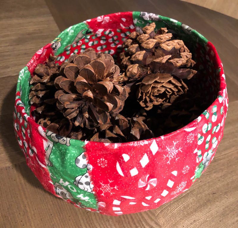 Fabric Christmas bowl filled with pinecones on a table
