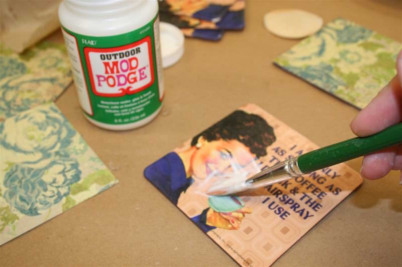 Paint Mod Podge Outdoor on the top of a dollar coaster with a paintbrush