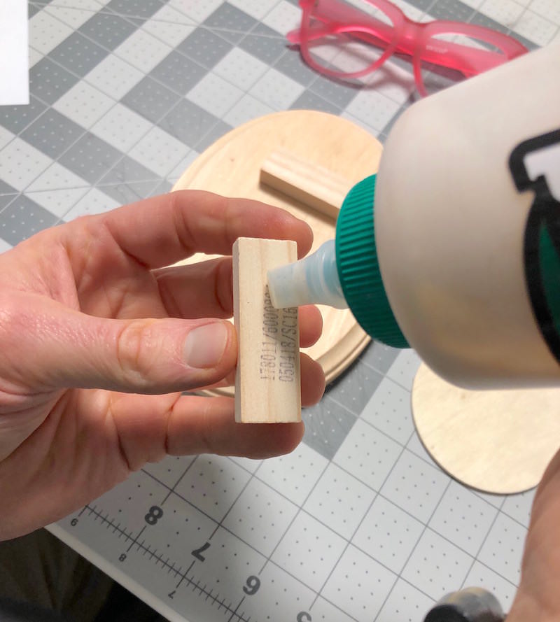Placing wood glue on the back of a small piece of wood