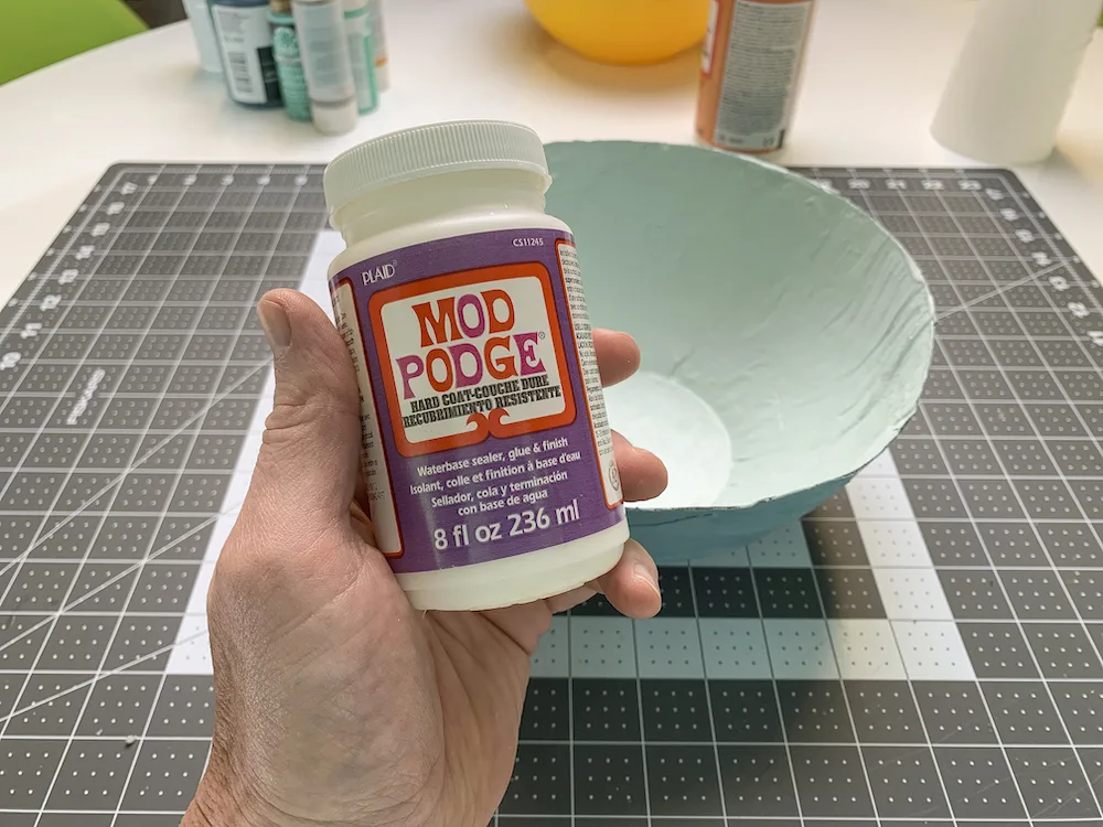 Mod Podge hard coat with a newspaper bowl in the background