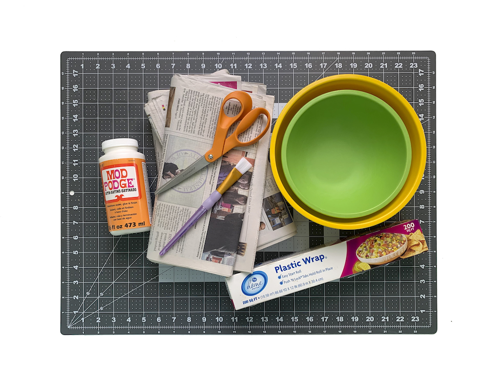 Mod Podge newspaper bowls plastic wrap and paintbrushes