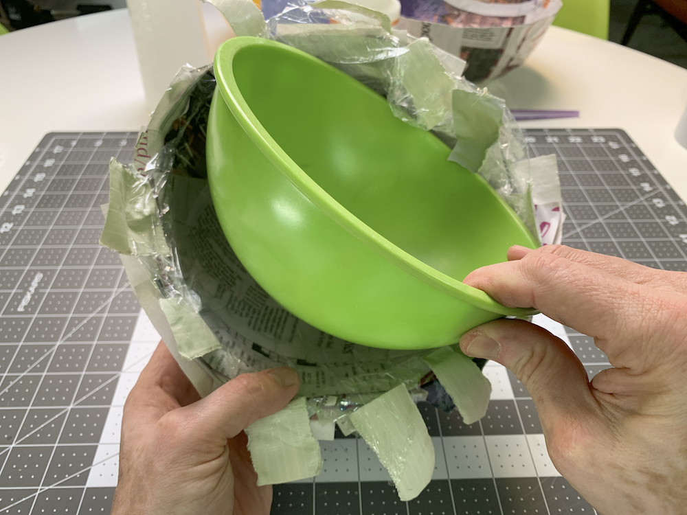 Removing a green bowl from a paper mache cast