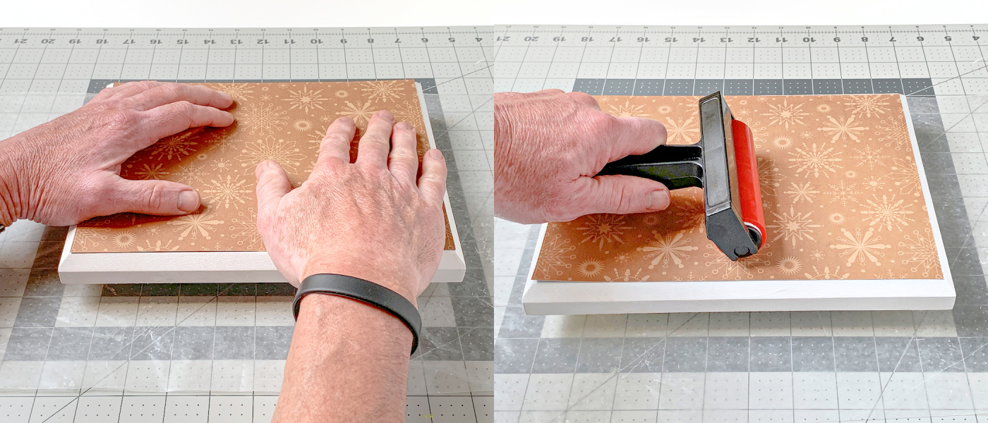 Smoothing down paper onto a wood plaque using hands and a brayer