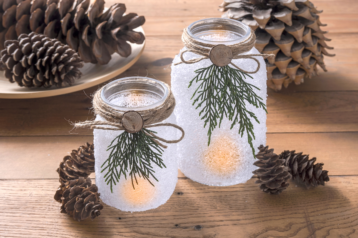 Lighted mason jar Christmas luminaries in front of pinecones