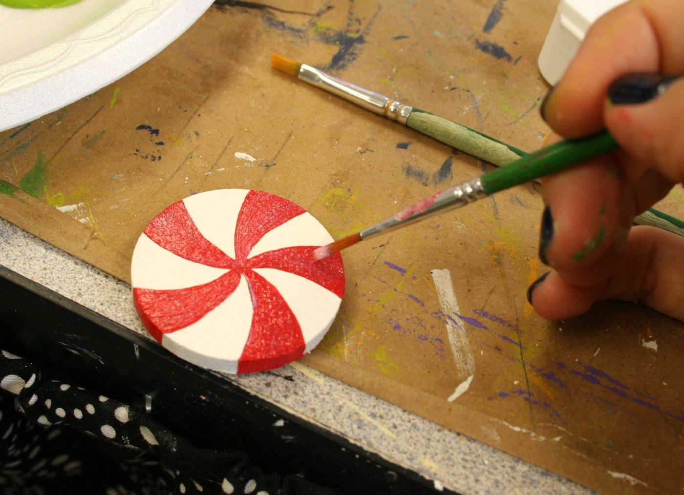Painting a wood circle with red paint to look like a peppermint