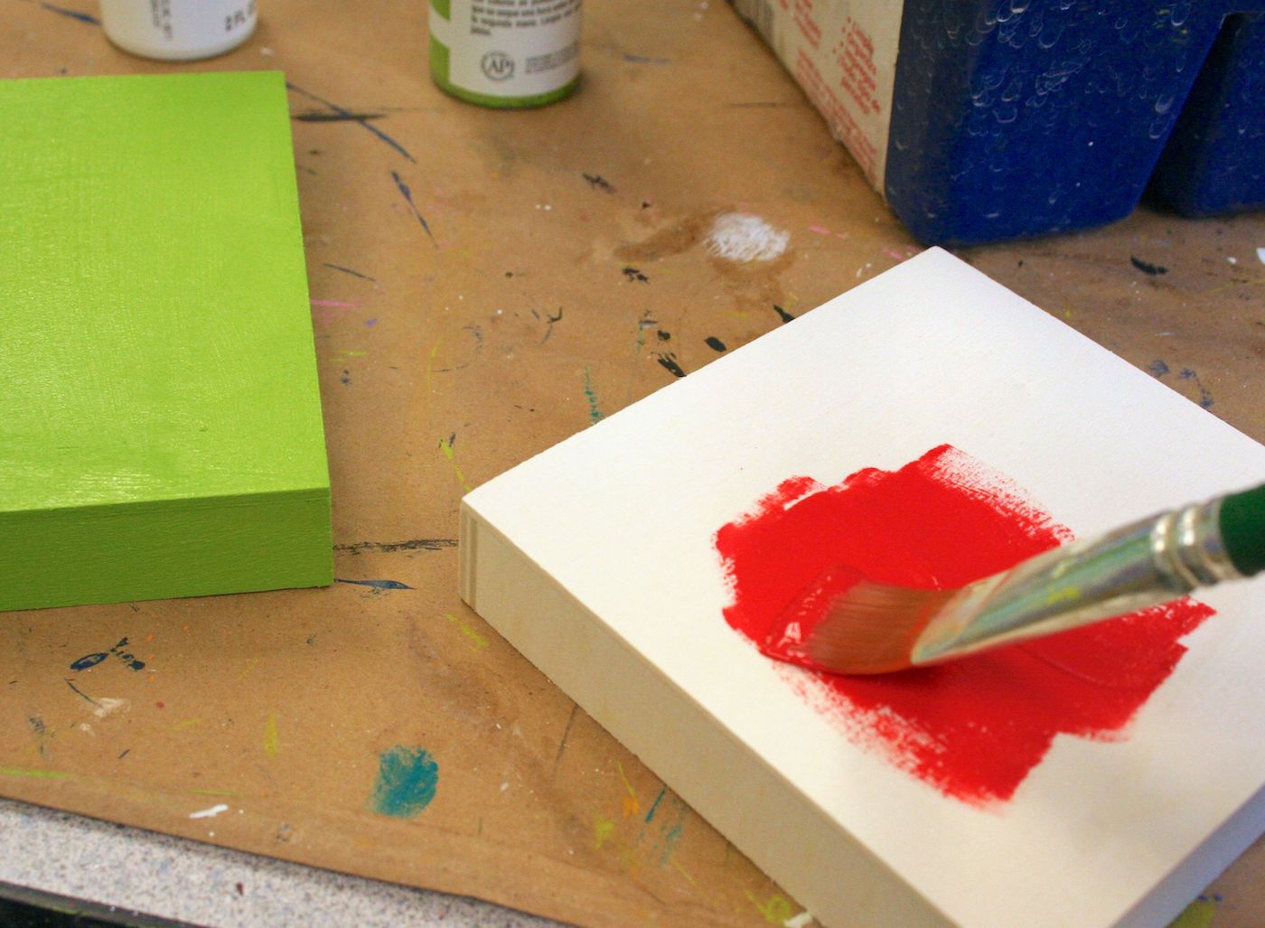 Painting the lid of a wood box with red craft paint