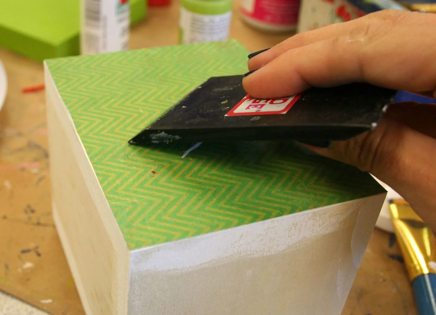 Smoothing paper down onto the side of a wood box with a squeegee