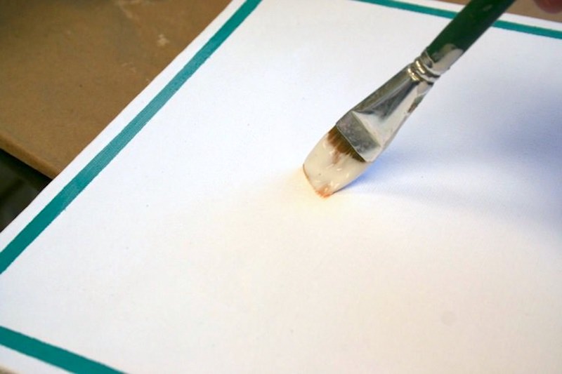 Sealing the canvas with a coat of Mod Podge using a paintbrush