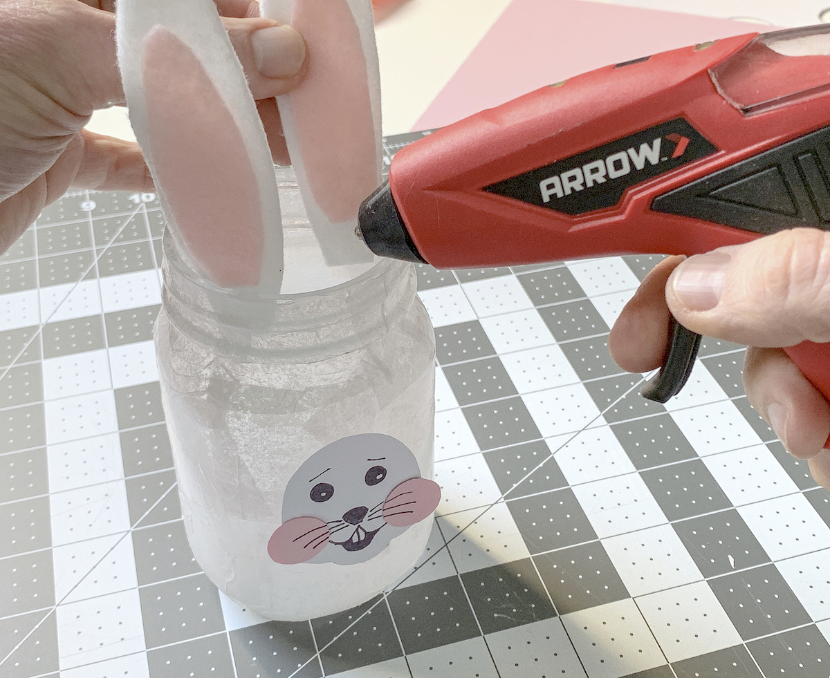 Applying the ears to the Easter mason jars with hot glue