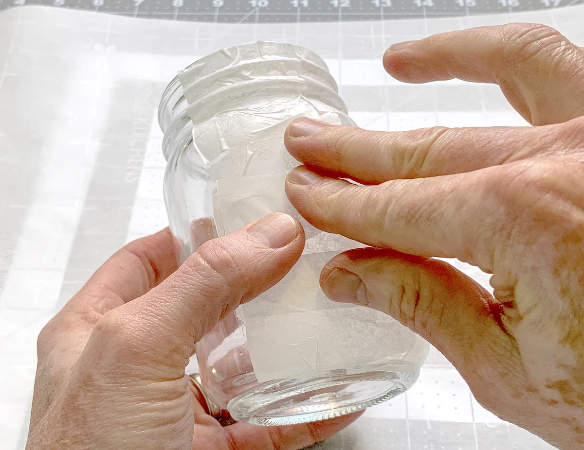 Smoothing tissue paper down onto the side of a mason jar