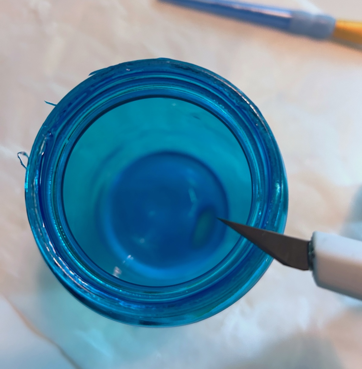 cutting the excess Mod Podge around the lip of a jar