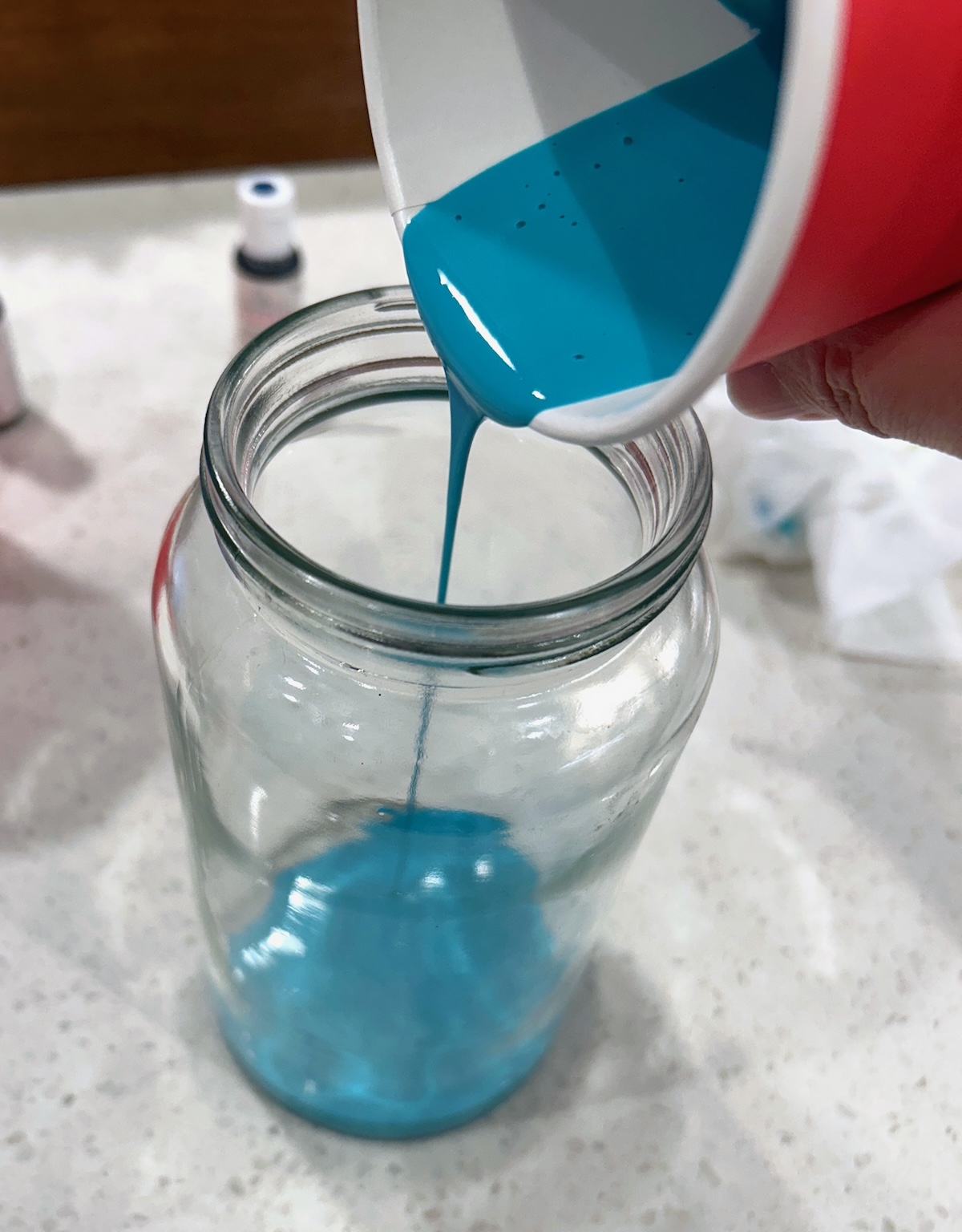 pouring mod podge and food coloring into a mason jar