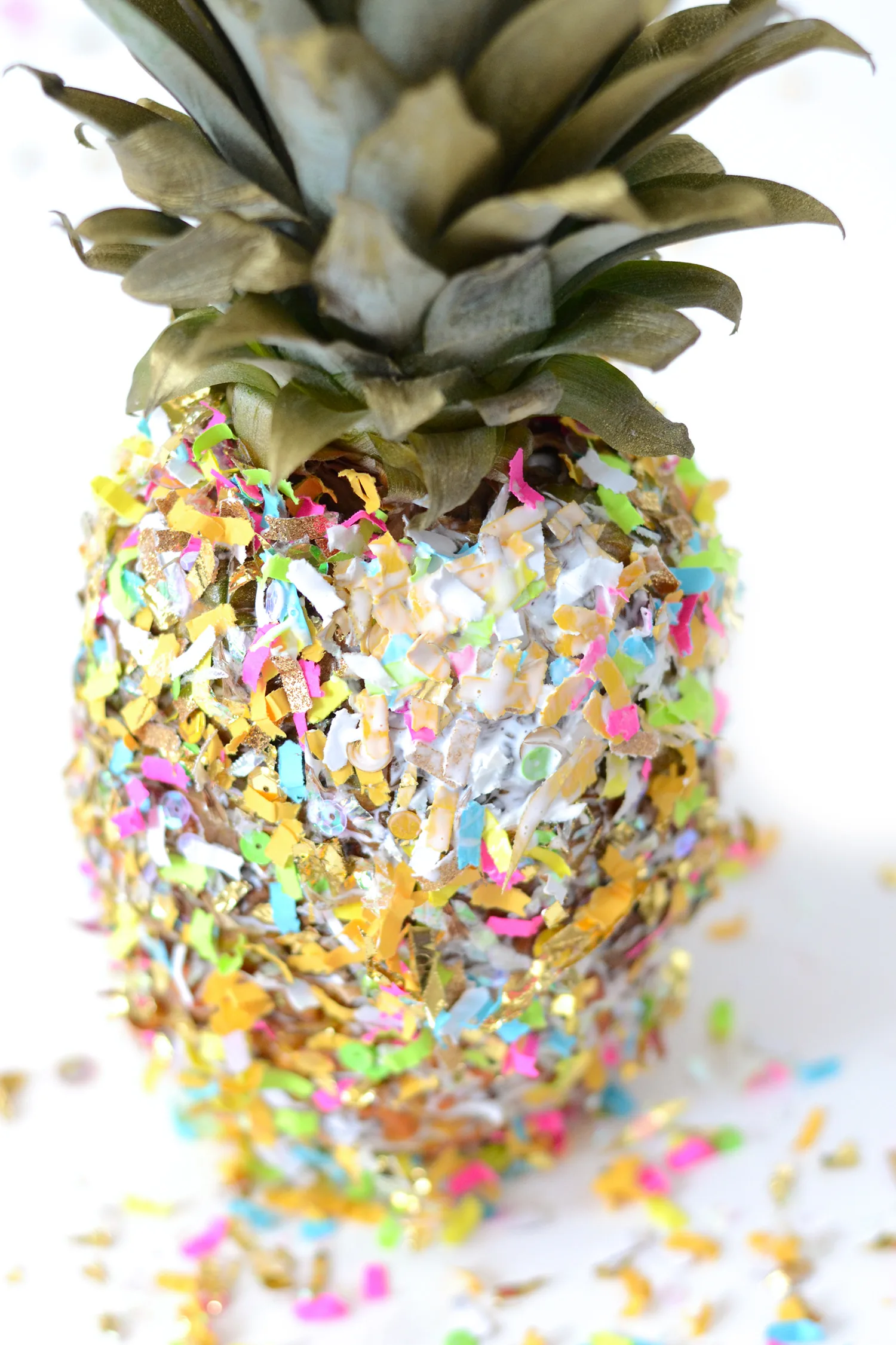 Touching up bare spots on a pineapple with Mod Podge and confetti