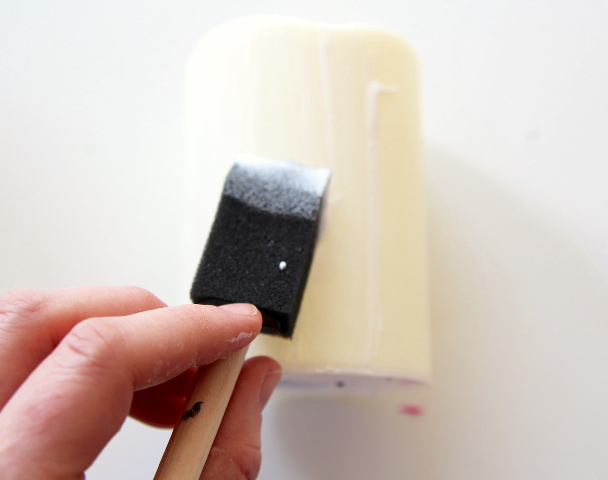 Adding Mod Podge to a candle with a foam brush