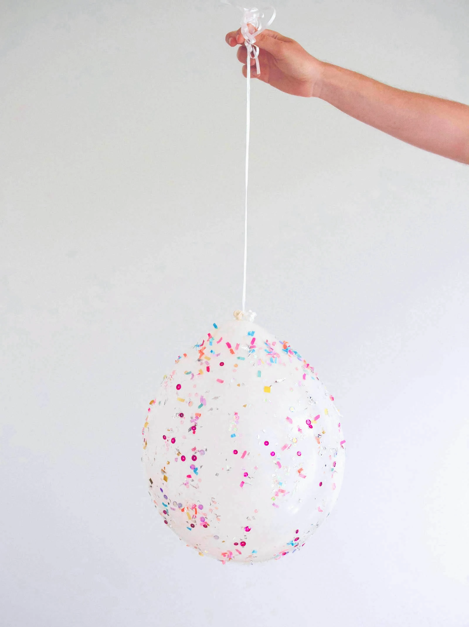 Hand holding a balloon covered with confetti