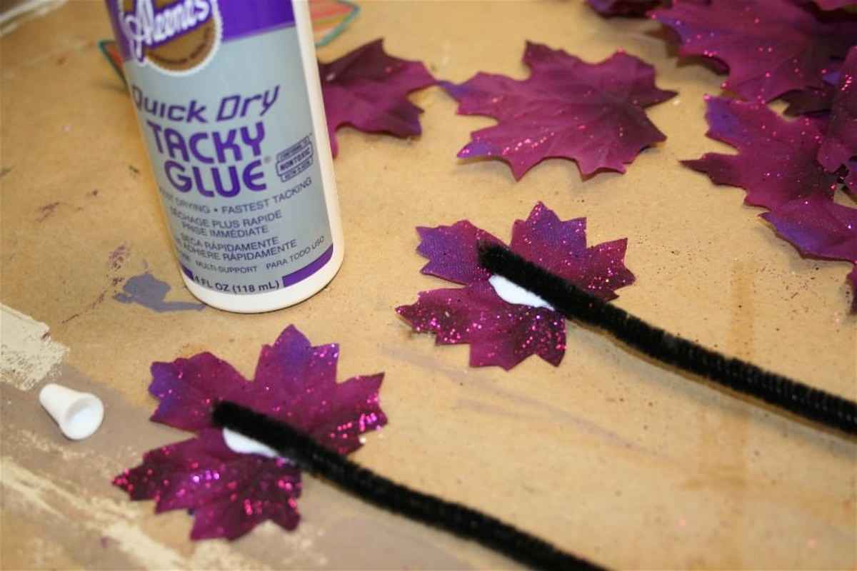 Gluing black pipe cleaners to purple sparkly leaves