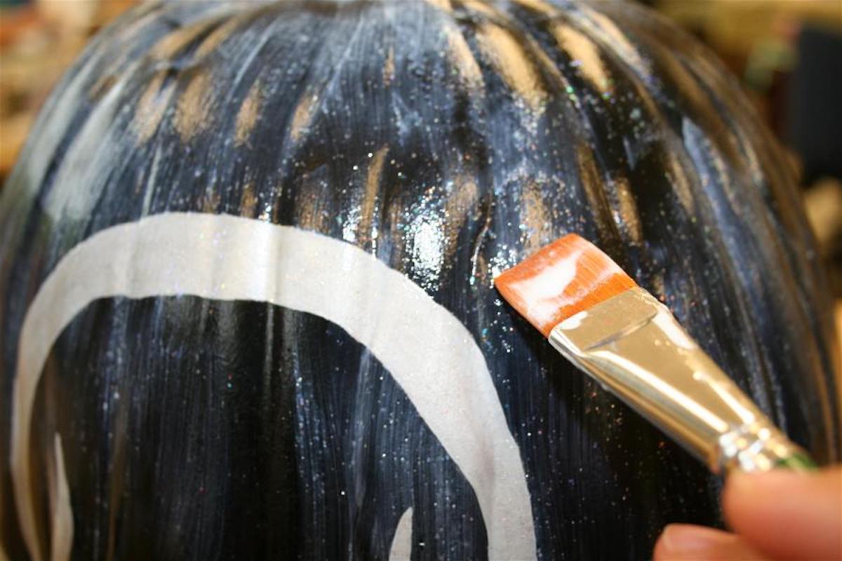 Painting sparkle mod podge over the top of the pumpkin