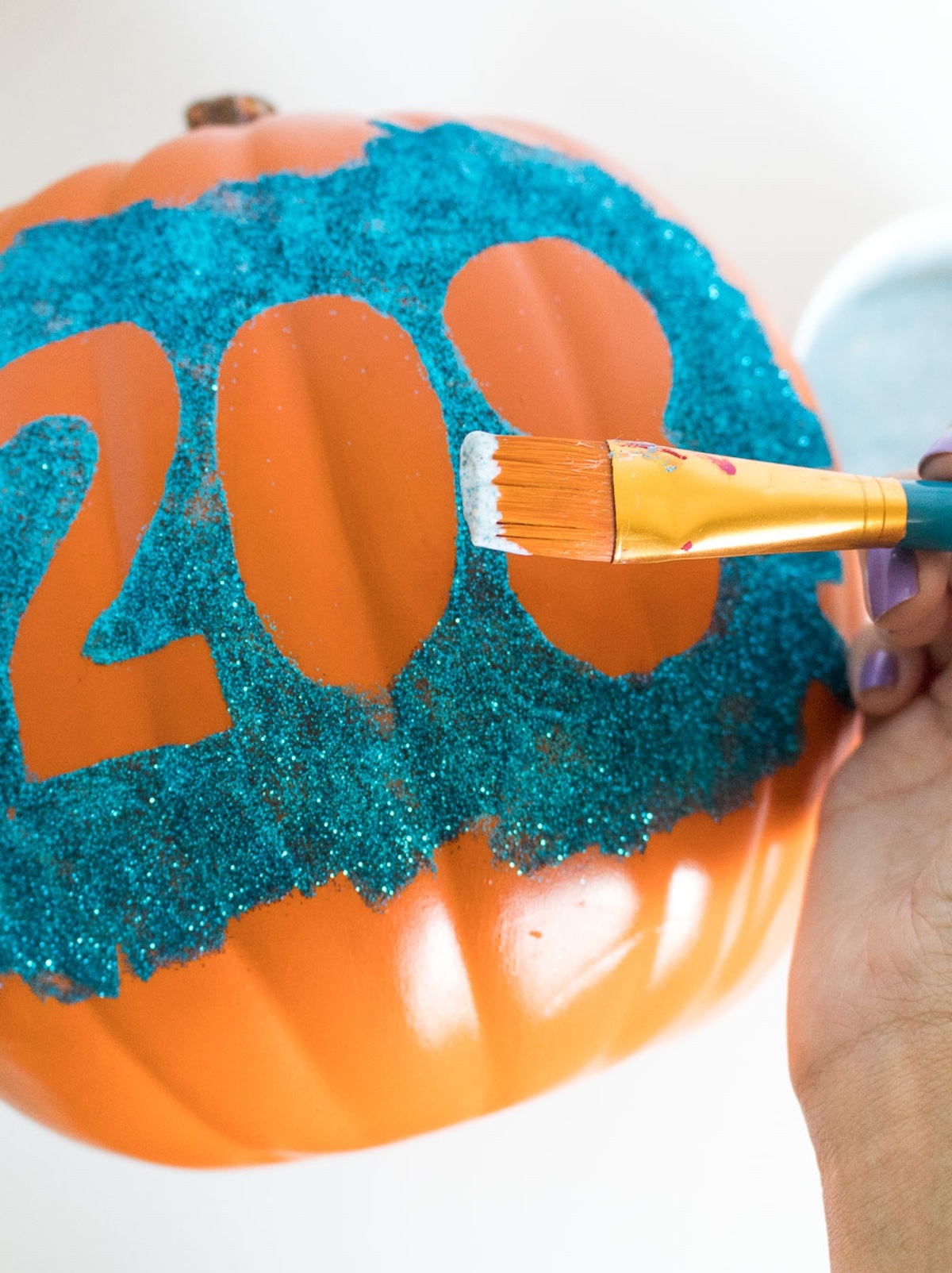 sealing the top o fthe glitter on the pumpkin with Mod Podge
