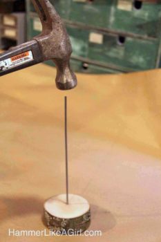 Making a base for the coasters by hammering a rod into a base piece of wood
