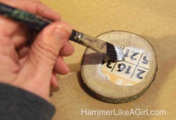 Mod Podge paper down onto wood slices with a paintbrush