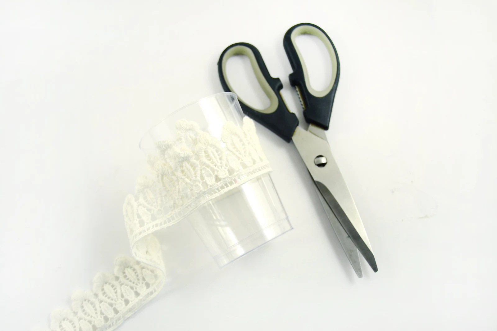 Pair of scissors and lace wrapped around a cup