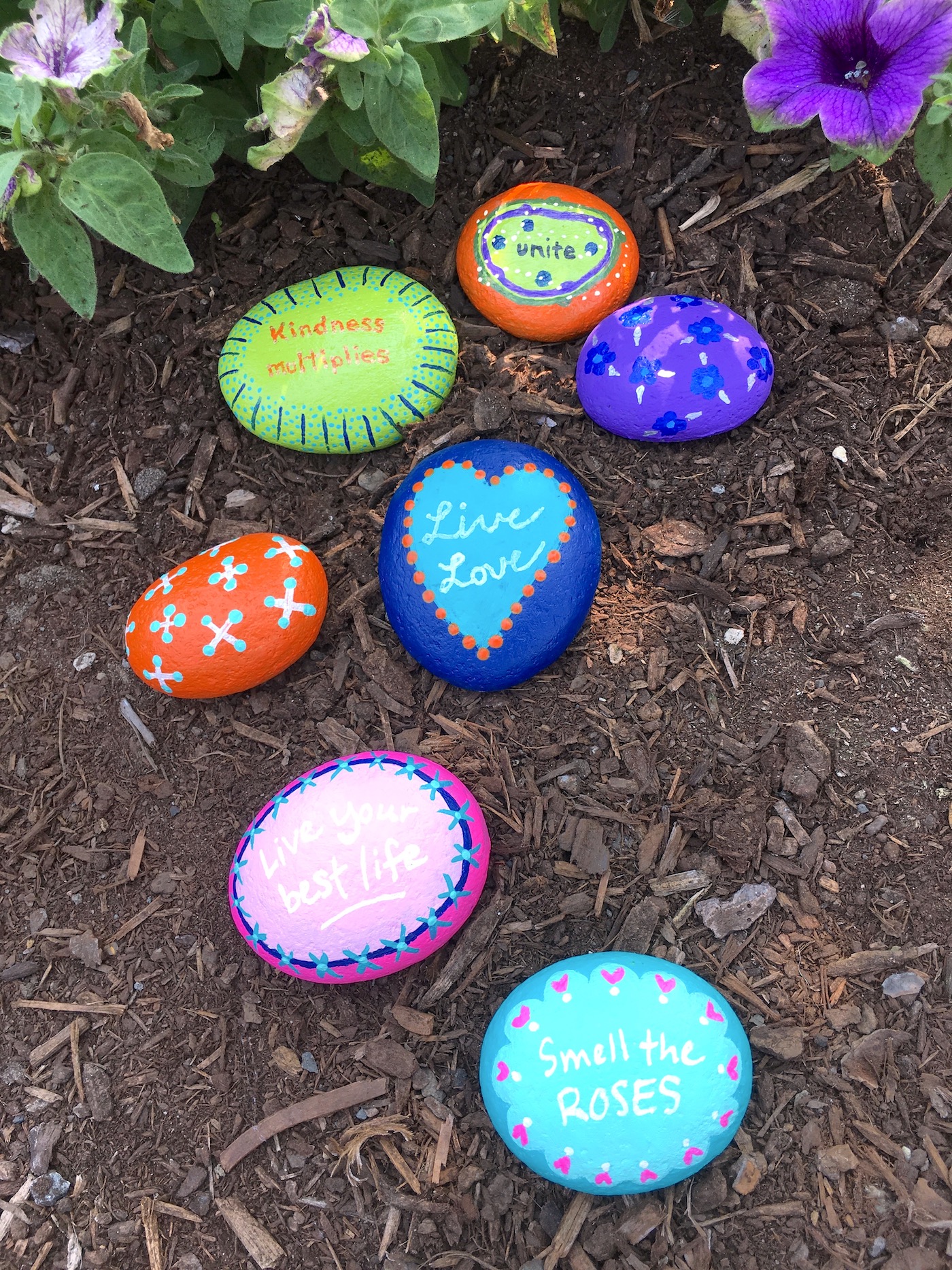 painted rocks laying in a garden bed