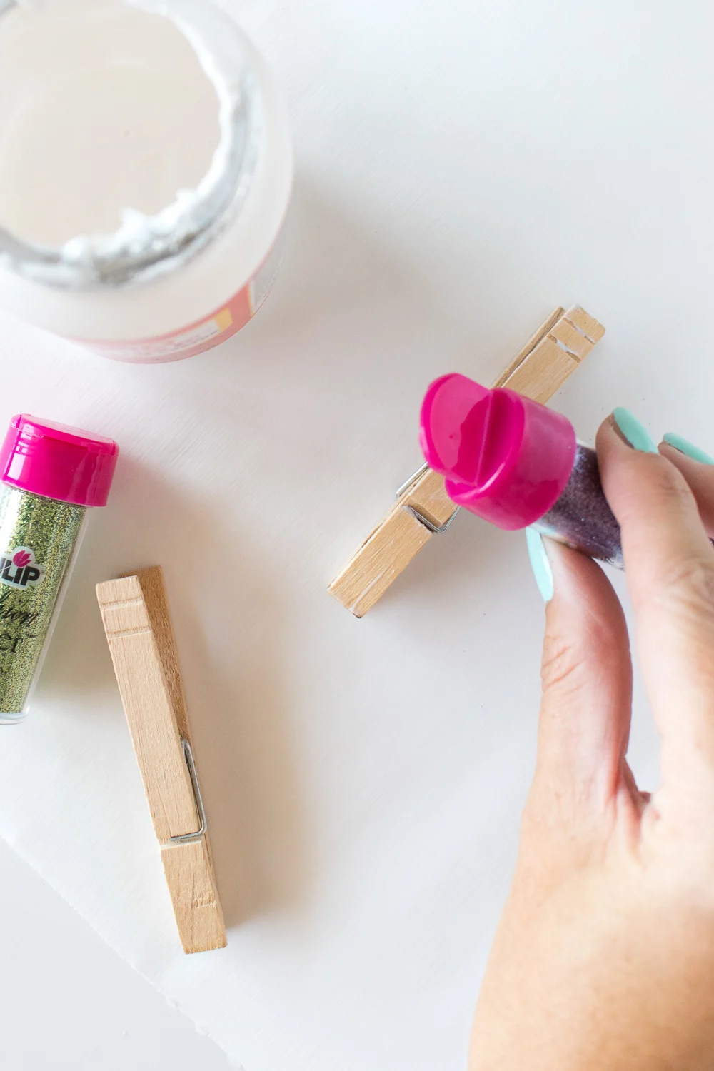 sprinkling glitter on the top of clothespins