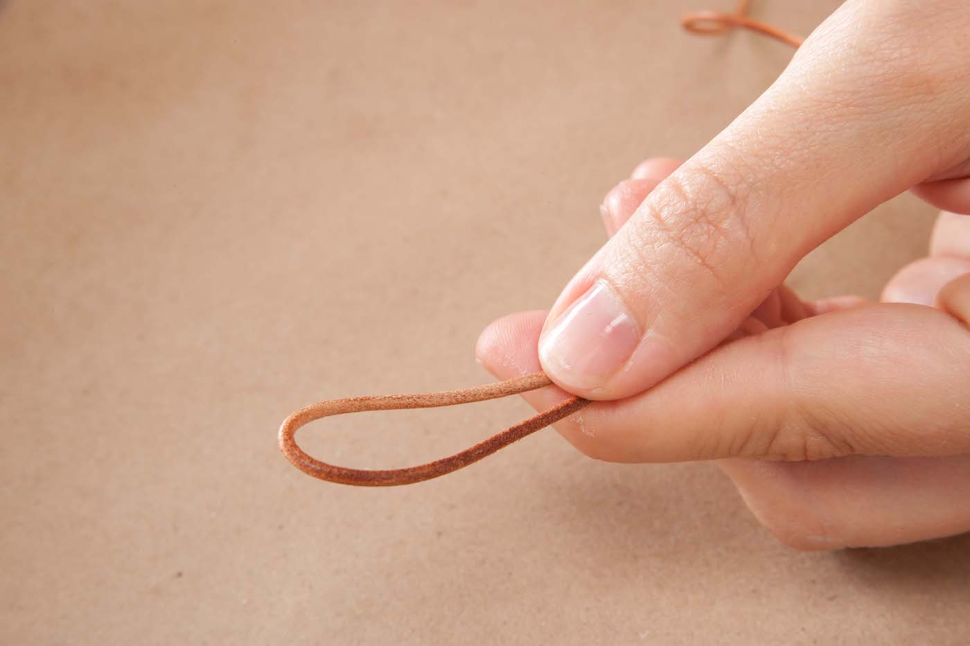 Fingers holding a leather cord in a loop