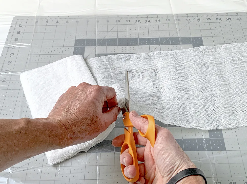 Cutting cheesecloth with a pair of scissors