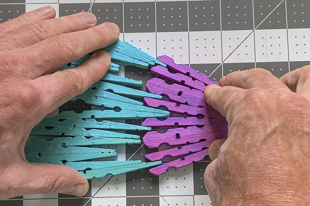 Hands fitting clothespins together to create a wing
