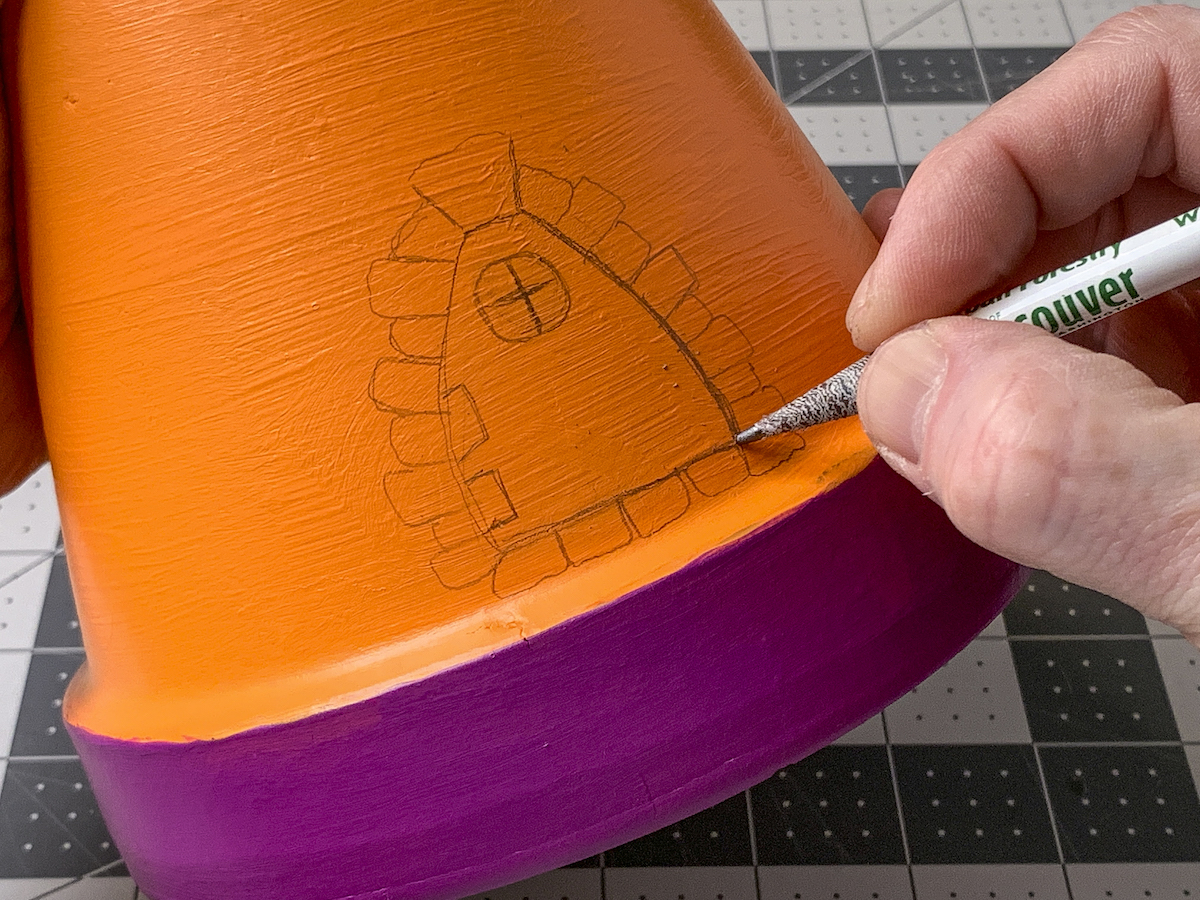 Drawing a fairy door onto a pot with a pencil
