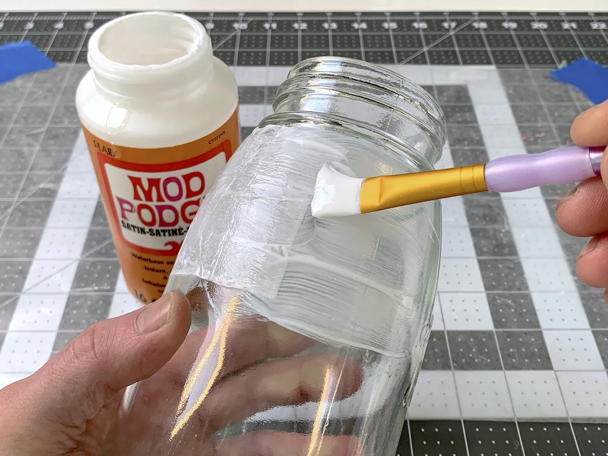 Painting Mod Podge onto the side of a mason jar