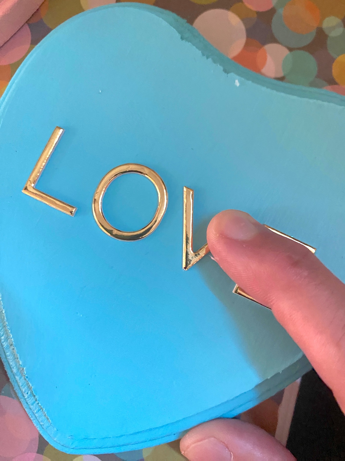Applying gold letters to the top of the blue heart