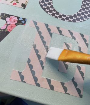 Applying Mod Podge on top o fthe letter E on a canvas