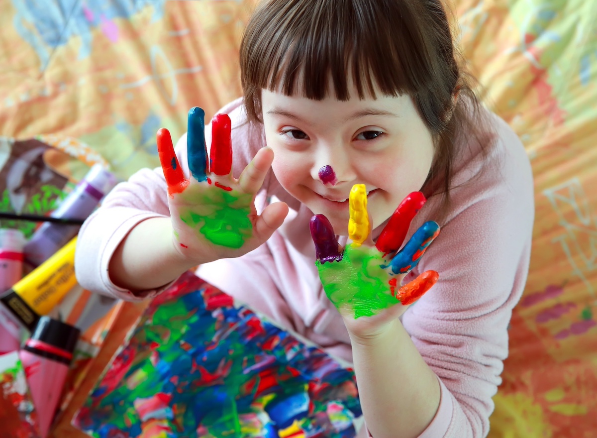 Child-with-downs-syndrome-showing-painted-hands
