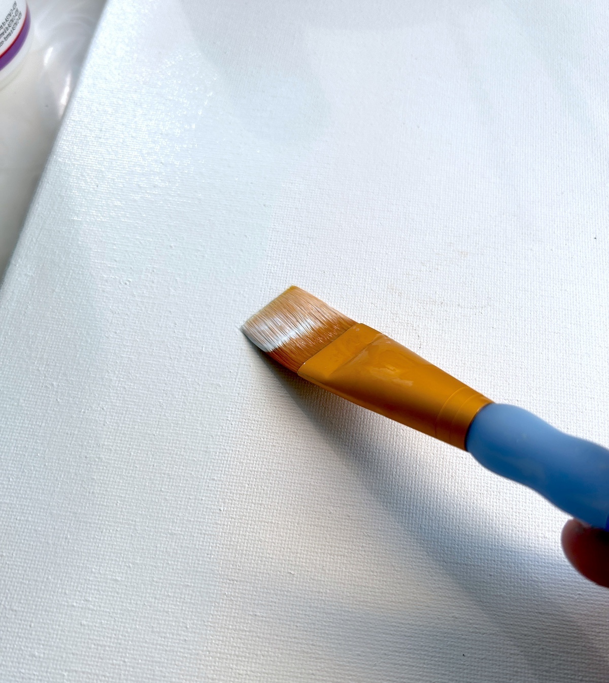 Painting a canvas with light blue acrylic paint