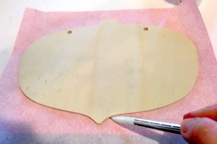 Tracing a wood ornament shape onto tissue paper with a pencil
