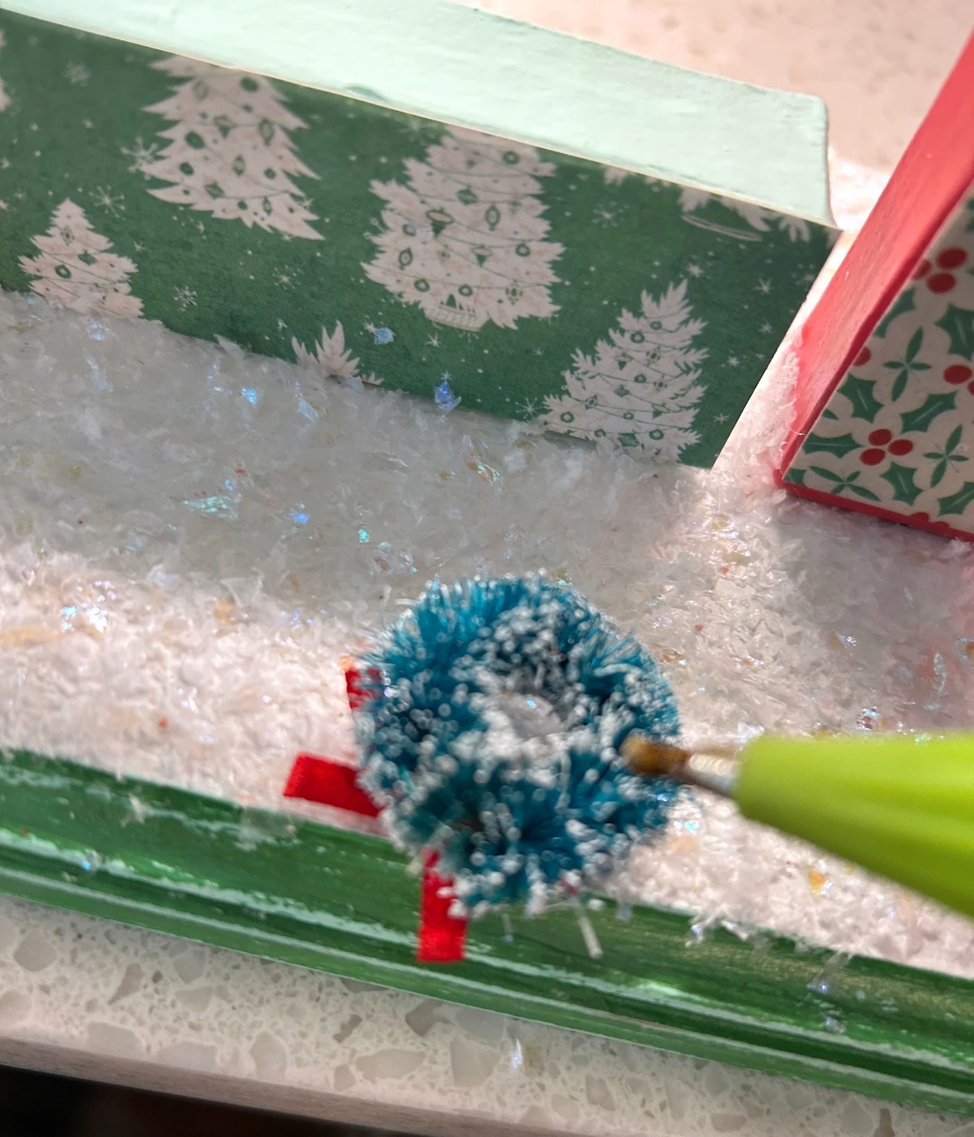 Hot gluing a wreath to the front of a letter