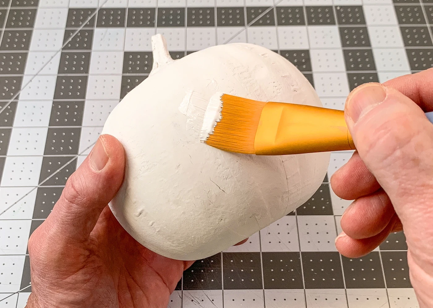 Painting a paper mache craft pumpkin with white craft paint