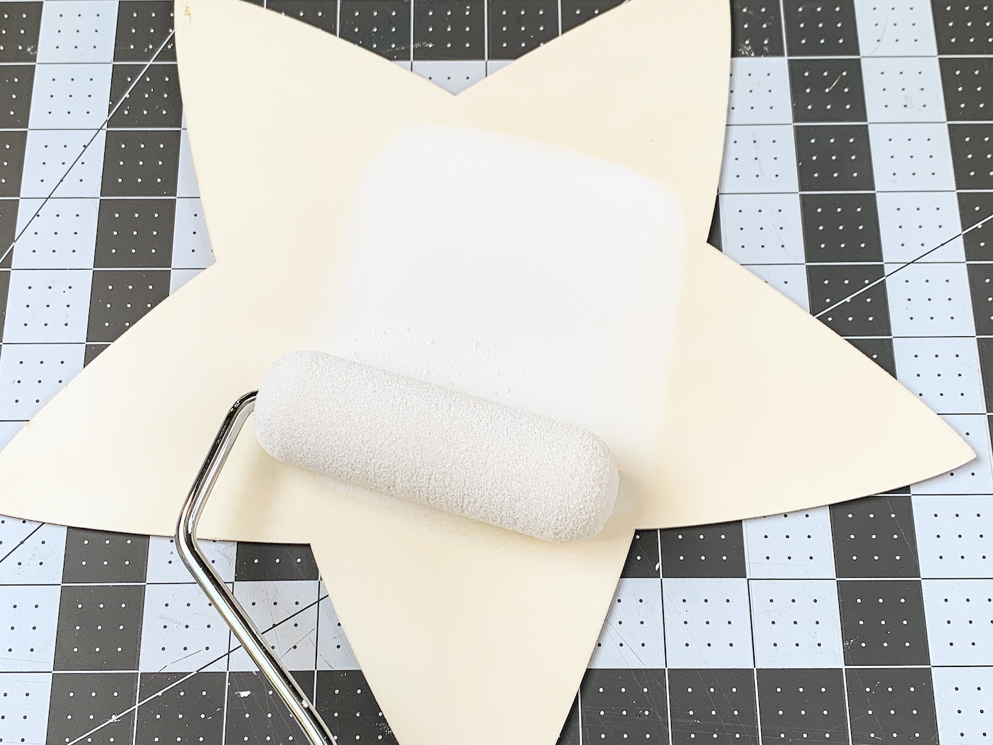 Painting a wood star with white using a foam roller